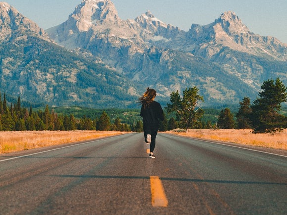 Female runner on road leading to mountains